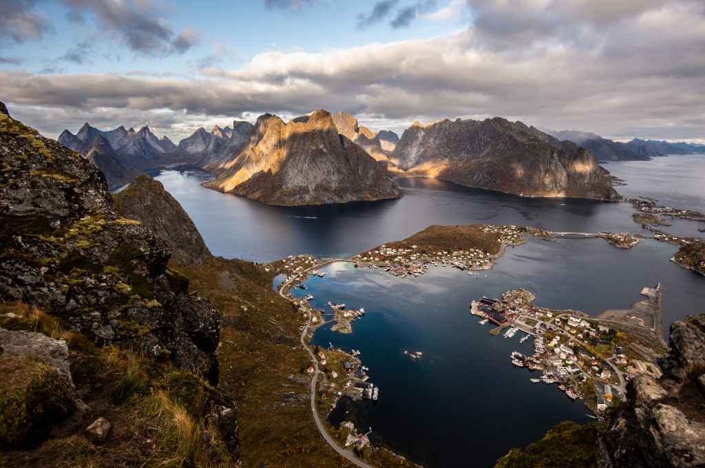 Red fishing cabins of Reine village reflected in still water, Lofoten Islands, Norway