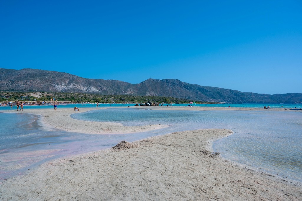Wide shallow turquoise lagoon at Elafonissi Beach, Crete, with mountain backdrop